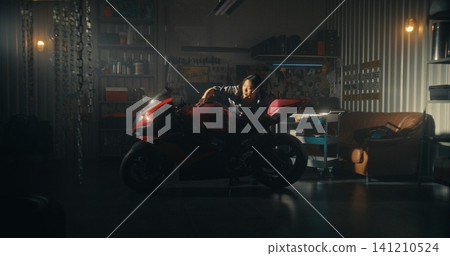Woman Lovingly Clean Motorcycle in Modern Garage Filled With Golden Light Woman Lovingly Clean Motorcycle in Modern Garage Filled With Golden Light 141210524