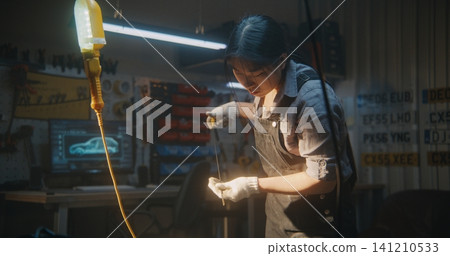 Female Auto Mechanic Checking Oil Level With Dipstick in Workshop Female Auto Mechanic Checking Oil Level With Dipstick in Workshop 141210533