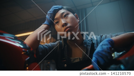 In Garage, Young Mechanic Pauses Beside Motorcycle, Thinking Intensely About How Fix Malfunction In Garage, Young Mechanic Pauses Beside Motorcycle, Thinking Intensely About How Fix Malfunction 141210570