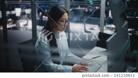 Female Financial Specialist Sits at Innovative Workspace, Eyes Scanning Multiple Displays Female Financial Specialist Sits at Innovative Workspace, Eyes Scanning Multiple Displays 141210652