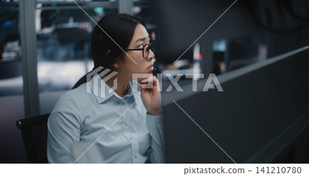 Professional Woman in Glasses and Headset, Intently Watching Fluctuating Stock Indices Professional Woman in Glasses and Headset, Intently Watching Fluctuating Stock Indices 141210780
