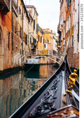 Rowing through a narrow canal in Venice with colorful buildings on both sides Rowing through a narrow canal in Venice with colorful buildings on both sides 141210870