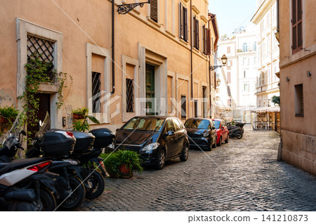 Cars and motorcycles parked along a narrow street in Rome during the day Cars and motorcycles parked along a narrow street in Rome during the day 141210873