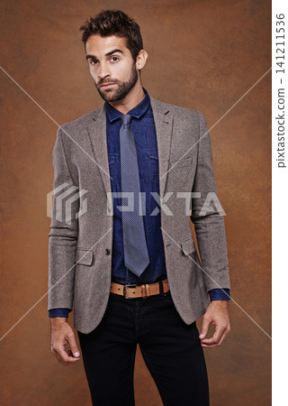 Suit, style and portrait of man in studio with confidence for trendy, classy and stylish outfit. Cool, fashion and male model with pride for elegant, fancy or luxury clothes by brown background. 141211536