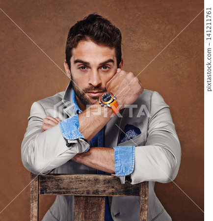 Fashion, watch and portrait of man in studio with trendy, stylish and classy suit on chair. Serious, time and handsome male person with elegant style for outfit and accessory by brown background. Fashion, watch and portrait of man in studio with trendy, stylish and classy suit on chair. Serious, time and handsome male person with elegant style for outfit and accessory by brown background. 141211761