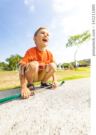 Boy plays outside with a stick in a park during a sunny day Boy plays outside with a stick in a park during a sunny day 141211800