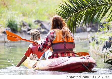 Kayaking on a sunny day with child in a calm water area surrounded by nature 141212013