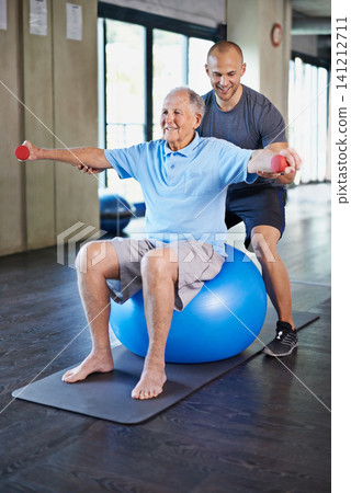 Physiotherapist, helping and senior man with dumbbell, training and elderly support for care. Men, gym and exercise for health, wellness and coaching with yoga ball for mature rehab and wellbeing Physiotherapist, helping and senior man with dumbbell, training and elderly support for care. Men, gym and exercise for health, wellness and coaching with yoga ball for mature rehab and wellbeing 141212711