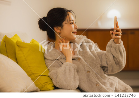 A young woman looking at her smartphone in the living room at night A young woman looking at her smartphone in the living room at night 141212746