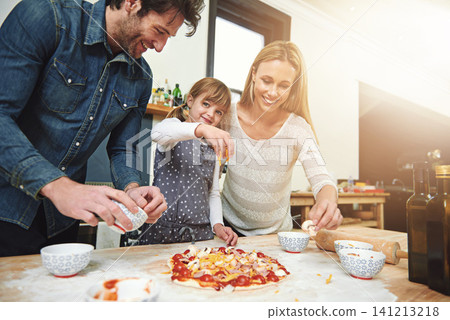 Portrait, child and happy family baking pizza in kitchen together, bonding and smile for learning in home. Face, mother and father with girl cooking, teaching and help parents with cheese at table 141213218