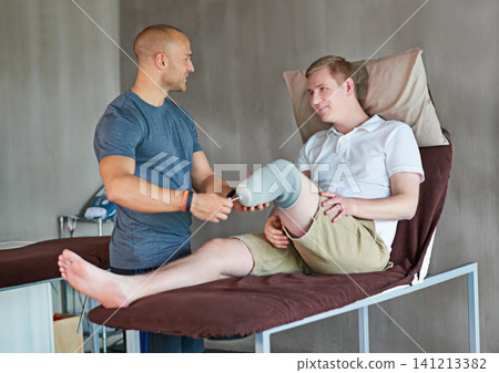 Therapist, man with disability or prosthetic as medical, recovery or fitting in hospital for health. Bed, patient or leg in exam, help or physio as healthcare, orthopedic or rehabilitation progress Therapist, man with disability or prosthetic as medical, recovery or fitting in hospital for health. Bed, patient or leg in exam, help or physio as healthcare, orthopedic or rehabilitation progress 141213382