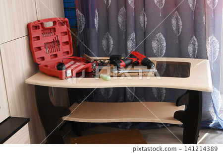 Tools and a small wooden table in a room with a cabinet and a curtain Tools and a small wooden table in a room with a cabinet and a curtain 141214389