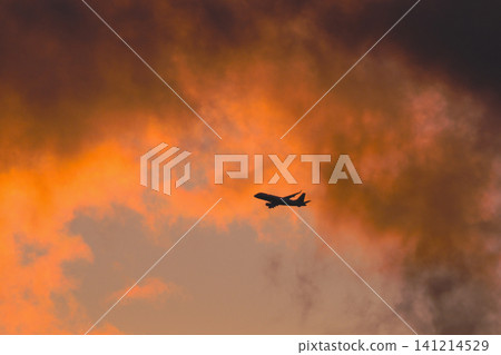 一架飛機飛向落日餘暉下的天空。 一架飛機飛向落日餘暉下的天空。 141214529