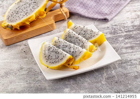 Sliced yellow dragon fruit on white plate with rustic background Sliced yellow dragon fruit on white plate with rustic background 141214955