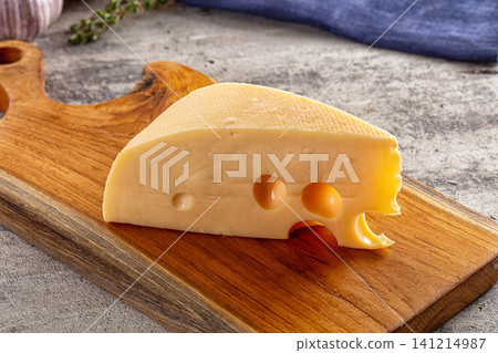 Wedged cheese with holes on wooden cutting board Wedged cheese with holes on wooden cutting board 141214987