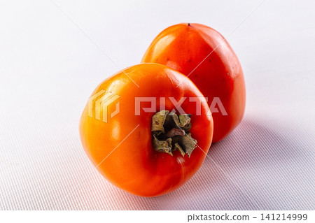 Two ripe persimmons on white textured surface Two ripe persimmons on white textured surface 141214999