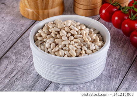 White beans in ceramic bowl with tomatoes and wooden grinders on rustic table White beans in ceramic bowl with tomatoes and wooden grinders on rustic table 141215003