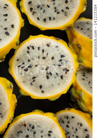Halved yellow dragon fruit showing white flesh and black seeds Halved yellow dragon fruit showing white flesh and black seeds 141215384