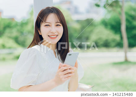 A young woman holding her smartphone on the terrace A young woman holding her smartphone on the terrace 141215480