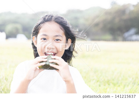 一位小學生小女孩正在開心地吃飯團體。 141215637