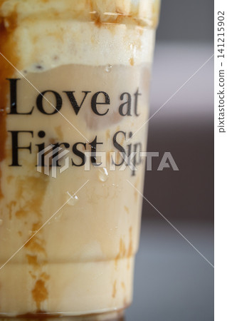 Macro shot of a plastic cup featuring condensation drops and text over iced coffee with caramel drizzle Macro shot of a plastic cup featuring condensation drops and text over iced coffee with caramel drizzle 141215902