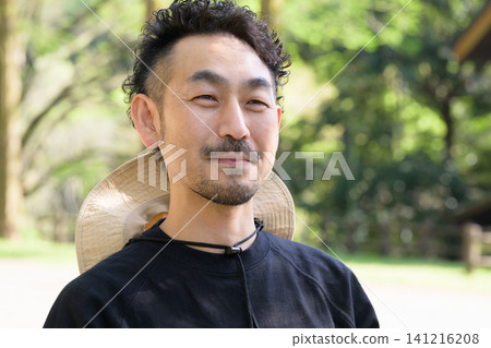 一位四十多歲、戴著草帽的男子在旅館前微笑。 一位四十多歲、戴著草帽的男子在旅館前微笑。 141216208