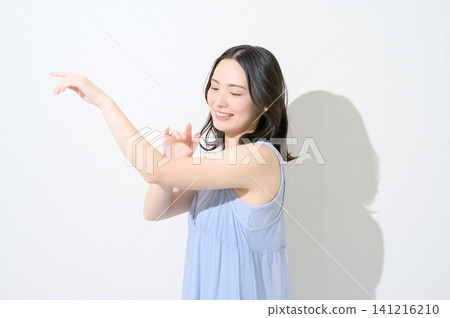 A beauty image of a Japanese woman applying sunscreen to her arm against a white background. A beauty image of a Japanese woman applying sunscreen to her arm against a white background. 141216210