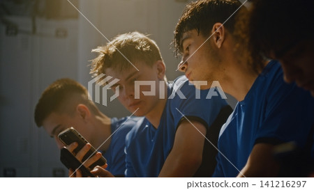 Teen Footballers Talking and Looking at Phone Screen in Locker Room Teen Footballers Talking and Looking at Phone Screen in Locker Room 141216297