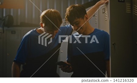 Teenage Football Players Watching Videos on Smartphone in Locker Room Teenage Football Players Watching Videos on Smartphone in Locker Room 141216320