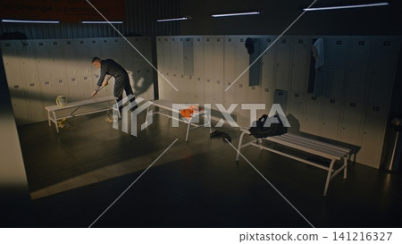 Male Janitor Mopping Floor and Cleaning Empty Sports Locker Room Male Janitor Mopping Floor and Cleaning Empty Sports Locker Room 141216327