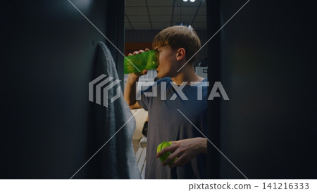 Young Footballer Putting Sports Bag in Locker and Drinking Young Footballer Putting Sports Bag in Locker and Drinking 141216333