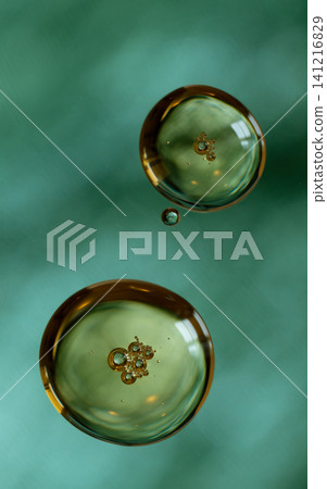 Oil drops creating a vibrant, translucent abstract pattern on a teal background Oil drops creating a vibrant, translucent abstract pattern on a teal background 141216829