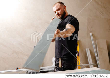Construction worker checking large ceramic tile during renovation works Construction worker checking large ceramic tile during renovation works 141216867