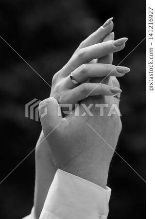 Close up of woman hand with ring resting on man hand in black and white romantic portrait style. Close up of woman hand with ring resting on man hand in black and white romantic portrait style. 141216927
