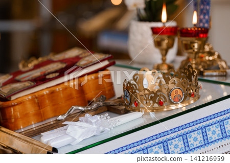 Golden Orthodox Baptismal Crowns and Holy Bible with Candles on Blue Embroidered Altar Cloth Golden Orthodox Baptismal Crowns and Holy Bible with Candles on Blue Embroidered Altar Cloth 141216959
