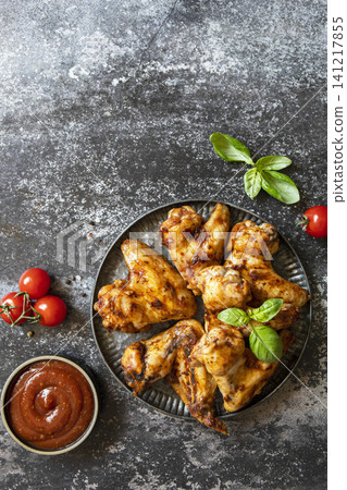 Barbecue chicken wings with sauce on a stone surface. Traditional baked bbq buffalo. Tasty snack for beer. Top view flat lay background. Copy space. Barbecue chicken wings with sauce on a stone surface. Traditional baked bbq buffalo. Tasty snack for beer. Top view flat lay background. Copy space. 141217855
