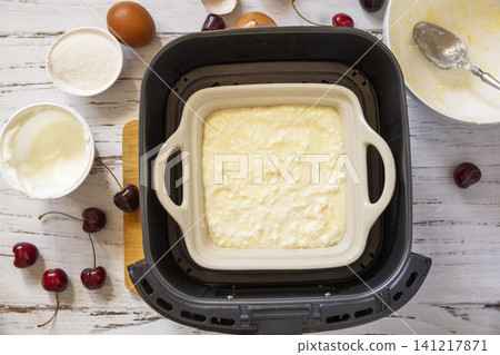 Step 6. The process of cooking cottage cheese casserole with cherries  in an air fryer, in kitchen gadget modern. Lifestyle trendy of new cooking. Healthy cooking with air fryer. 141217871