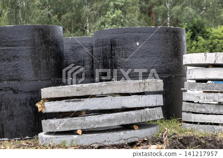 Workers are using the black and gray concrete blocks for a construction project. This site is located in an area with trees around it Workers are using the black and gray concrete blocks for a construction project. This site is located in an area with trees around it 141217957