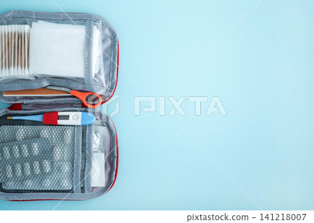 First aid kit open with medical supplies on blue background First aid kit open with medical supplies on blue background 141218007