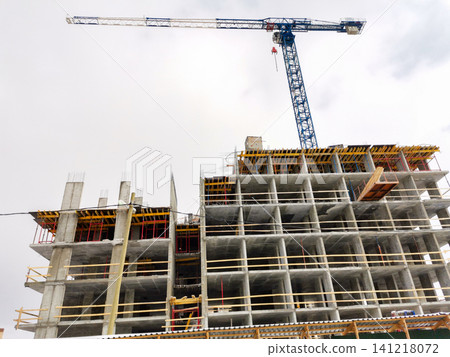 Construction site with concrete building framework and crane overhead Construction site with concrete building framework and crane overhead 141218072