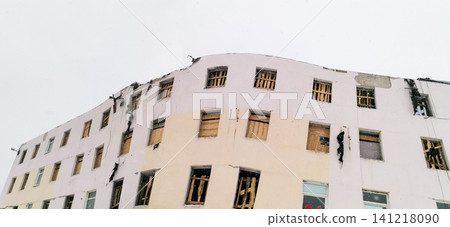 Damaged building facade with boarded windows and structural issues visible Damaged building facade with boarded windows and structural issues visible 141218090
