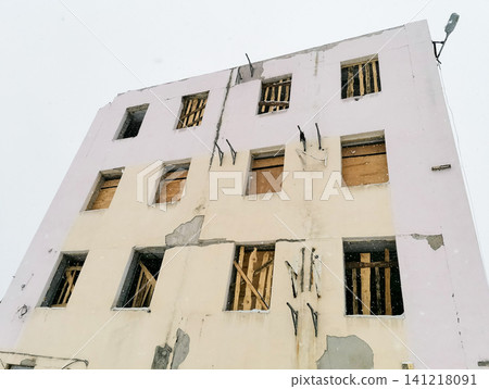 Abandoned building with boarded windows and peeling paint in winter Abandoned building with boarded windows and peeling paint in winter 141218091