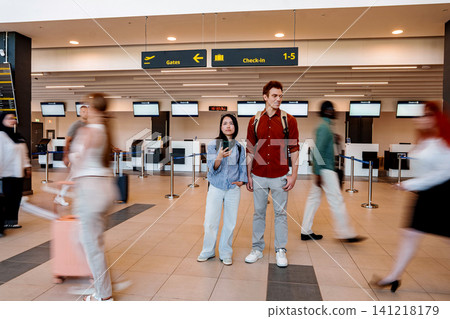 Couple standing in airport terminal while people rushing Couple standing in airport terminal while people rushing 141218179