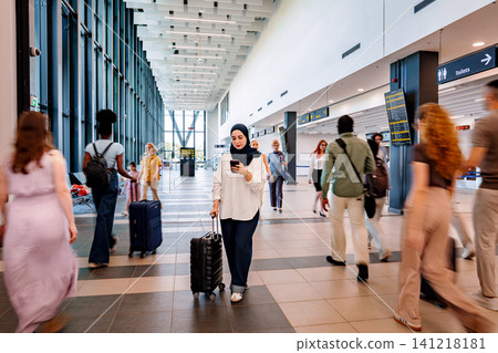Muslim woman checking phone while traveling through busy airport 141218181
