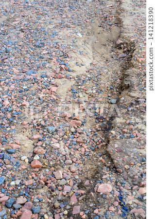 Crushed granite stones and sand texture on ground, eroded dirt path background with small pink and grey pebbles close up 141218390