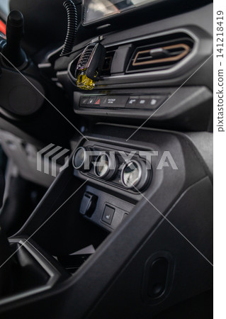 Close up of vehicle interior center dashboard layout, climate system, and manual gearbox. 141218419