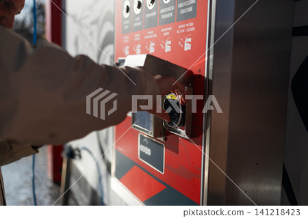 Hand pressing button on automated vending machine at manual carwash station. Hand pressing button on automated vending machine at manual carwash station. 141218423