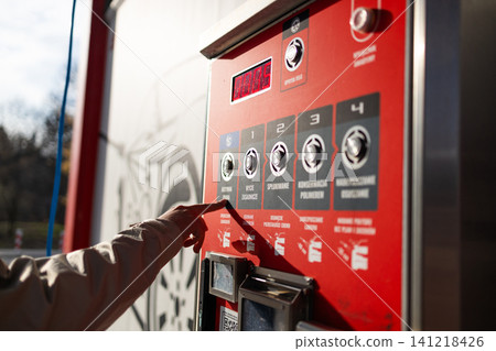 Hand pressing button on automated vending machine at manual carwash station. Hand pressing button on automated vending machine at manual carwash station. 141218426