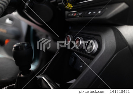 Close up of vehicle interior center dashboard layout, climate system, and manual gearbox. 141218431
