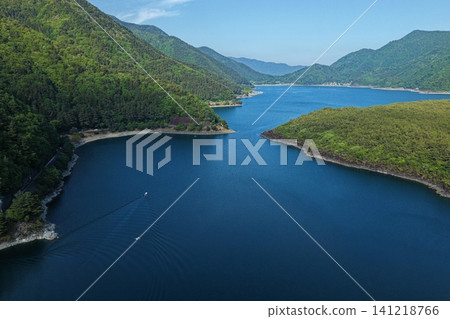 An aerial photograph showing Lake Saiko in Yamanashi Prefecture and the lush green mountains from a diagonal vantage point. An aerial photograph showing Lake Saiko in Yamanashi Prefecture and the lush green mountains from a diagonal vantage point. 141218766
